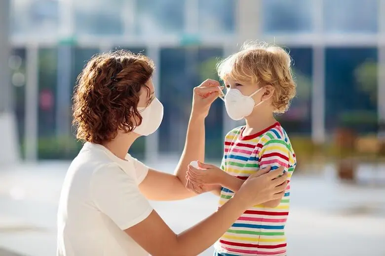 The Comprehensive Guide to COVID-19 7 A mother wearing a facemask puts a facemask on her young daughter